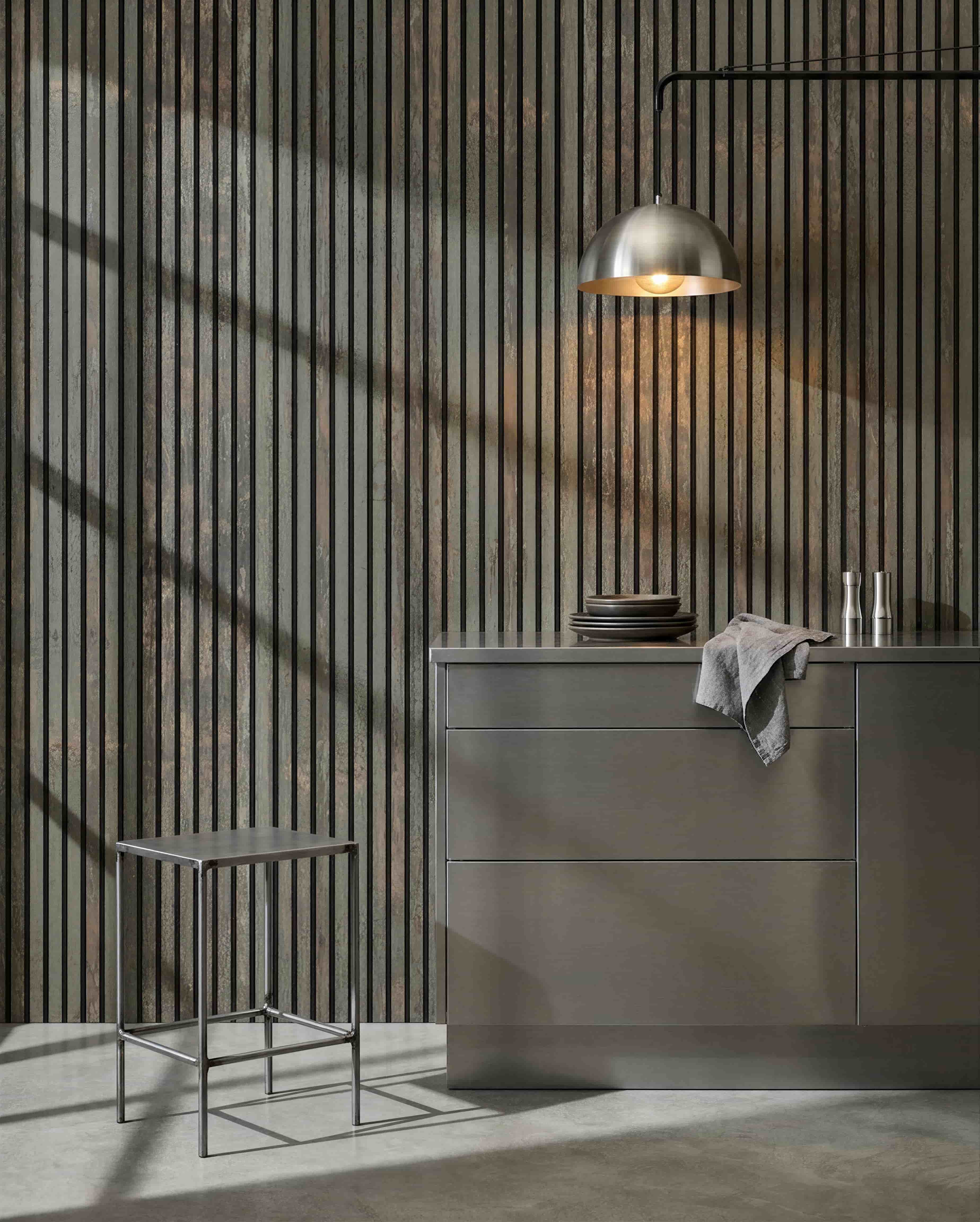 Minimalistische Küche mit Metallhocker, grey Kochinsel und Geschirr, mit einem WoodUpp Akupanel Akustik-Holzpaneel in Oxide Grey/Black Felt zur Schallkontrolle.