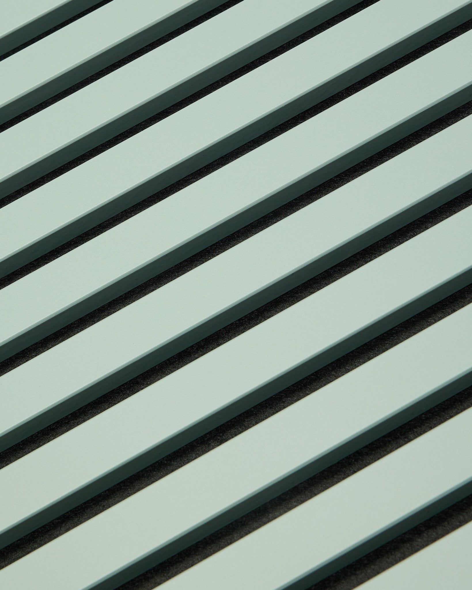 Hue | Akupanel / Cloud von WoodUpp zeigt hellgrüne Akustik-Holzpaneele mit vertical Lamellen und dunklen Zwischenräumen, die ein geometrisches Muster für die Schallabsorption bilden.