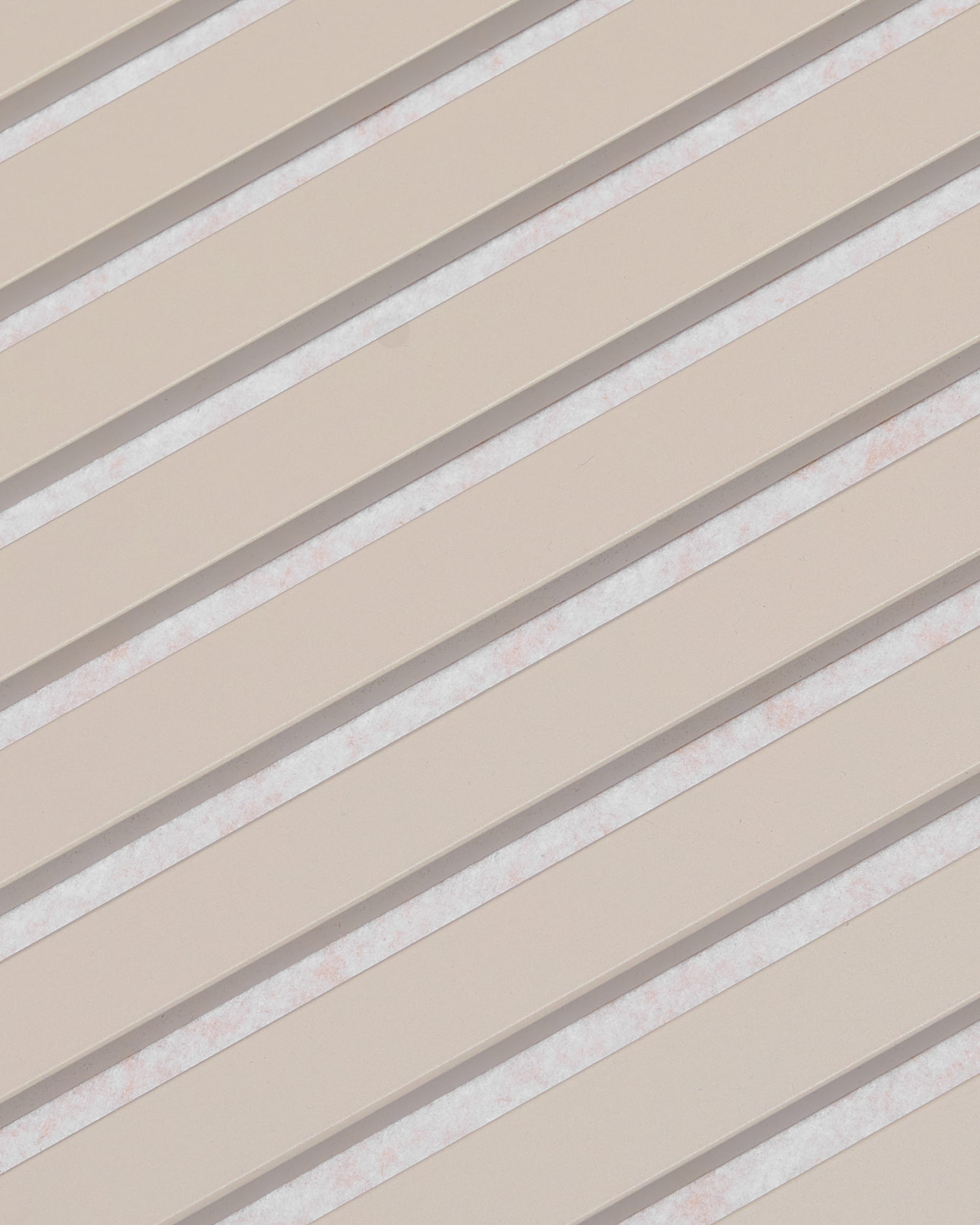 Diagonale beigefarbene Lamellen mit weißen Zwischenräumen bilden ein Streifenmuster auf der WoodUpp Akupanel-Akustikplatte mit der Oberflächenausführung „Soft Linen Light Beige Felt“, 240 x 60 cm.