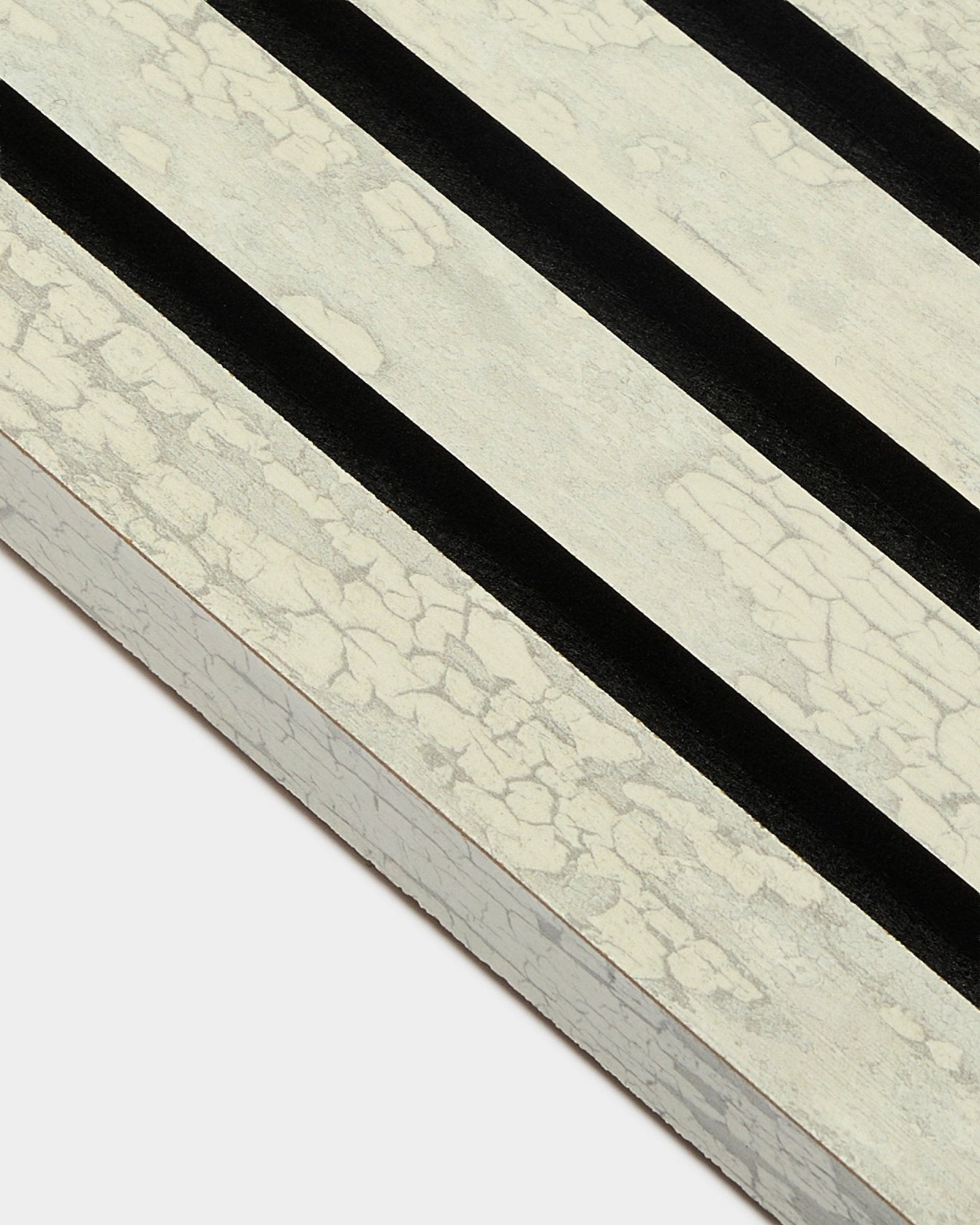 Nahaufnahme der WoodUpp Akupanel Endlamelle in Oxide White (2,2 cm) mit drei diagonalen black-Streifen auf einem MDF-Akustikpaneel-Rahmen.