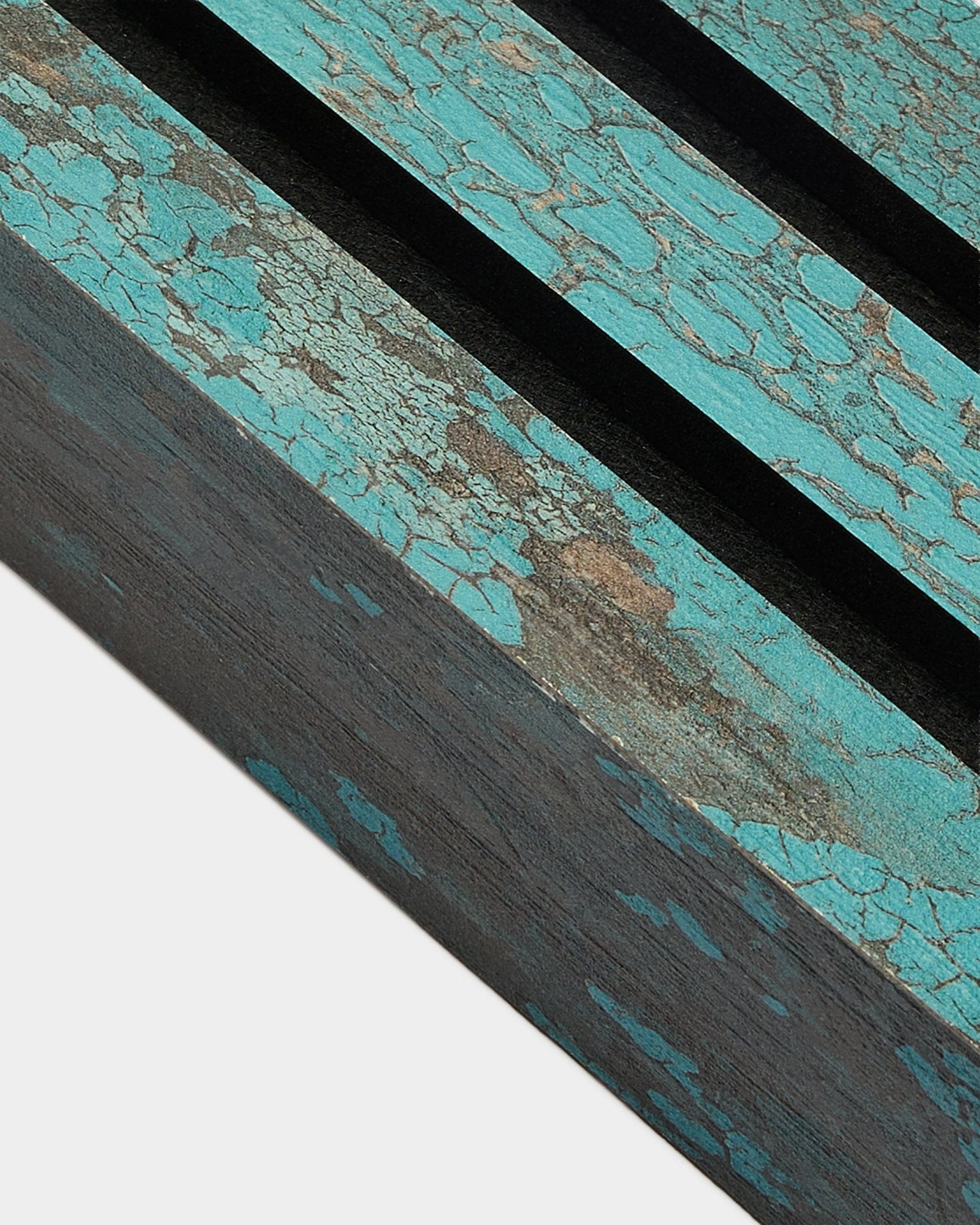 Nahaufnahme der WoodUpp Akupanel Abschlusslamelle in Oxide Blue, 6,7 cm breit, mit rissiger blauer Lackierung und black-Rillen auf einer rustikalen Akustikpaneel-Oberfläche.
