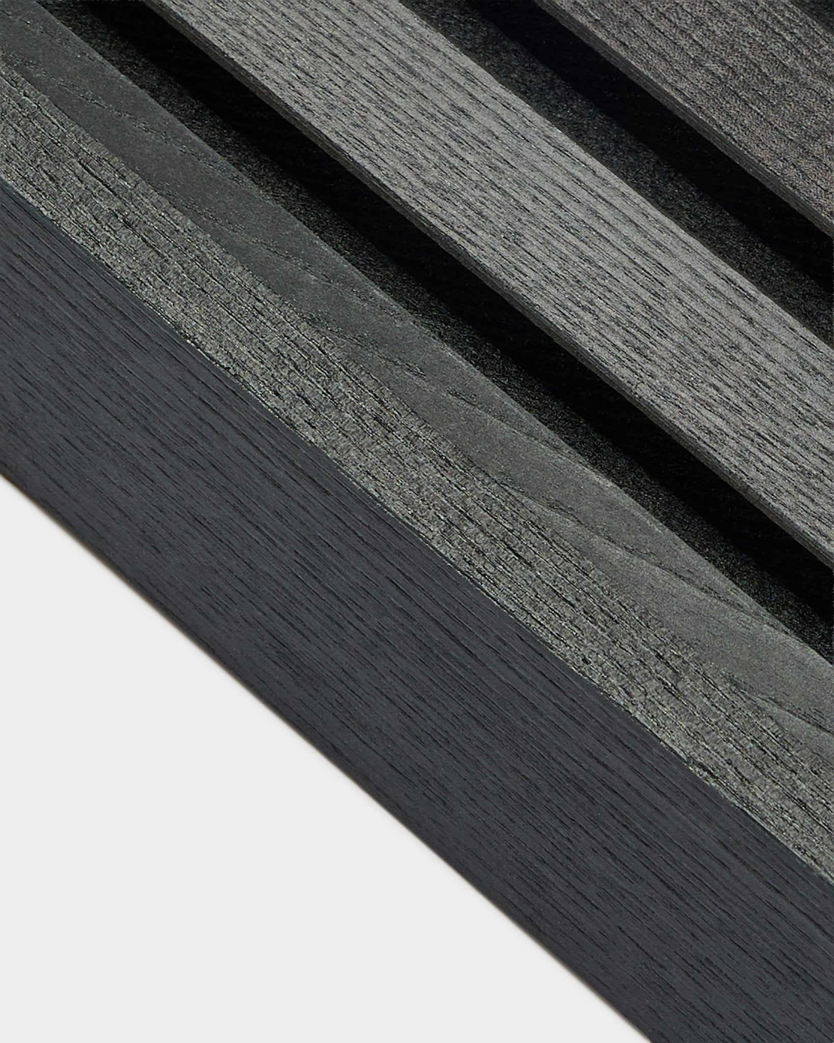 Nahaufnahme der WoodUpp Akupanel Abschlusslamelle in Black Esche (6,7 cm), mit dunkelgrauer Holzmaserung auf heller Basis, konzipiert für nordische Akustikpaneel Installationen.