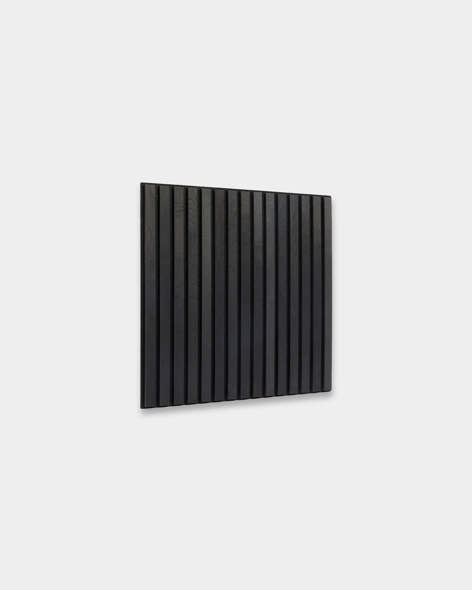 WoodUpp Akupixel Black Ash Akustikpaneel (60x60 cm) mit vertical Holzlamellen, montiert an einer hellgrauen Wand, zeigt minimalistisches skandinavisches Design.