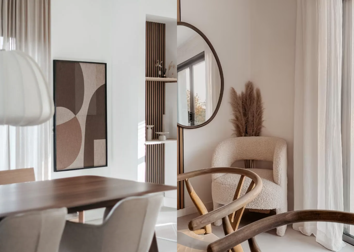 Minimalistischer nordischer Wohnbereich mit neutralen Tönen, Akupanel-Akustikholzpaneel als Wandkunst, rundem Spiegel, beigem Akzentsessel, Esstisch aus Holz und Pampasgras als Tafelaufsatz.