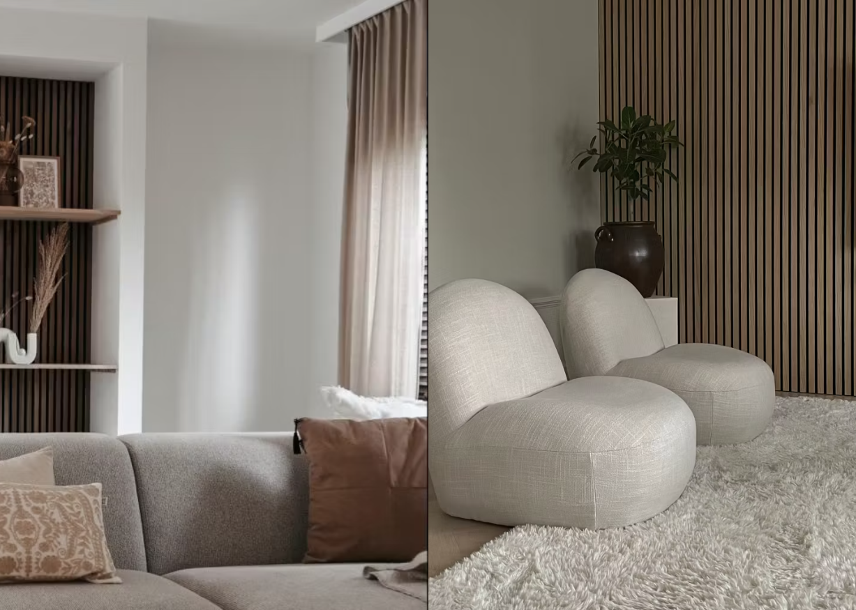 Modernes Wohnzimmer mit Sofas in neutralen Farbtönen, strukturiertem Teppich und einer Akustikwand aus Holzlatten, die von großen Fenstern mit sanftem Tageslicht beleuchtet wird.