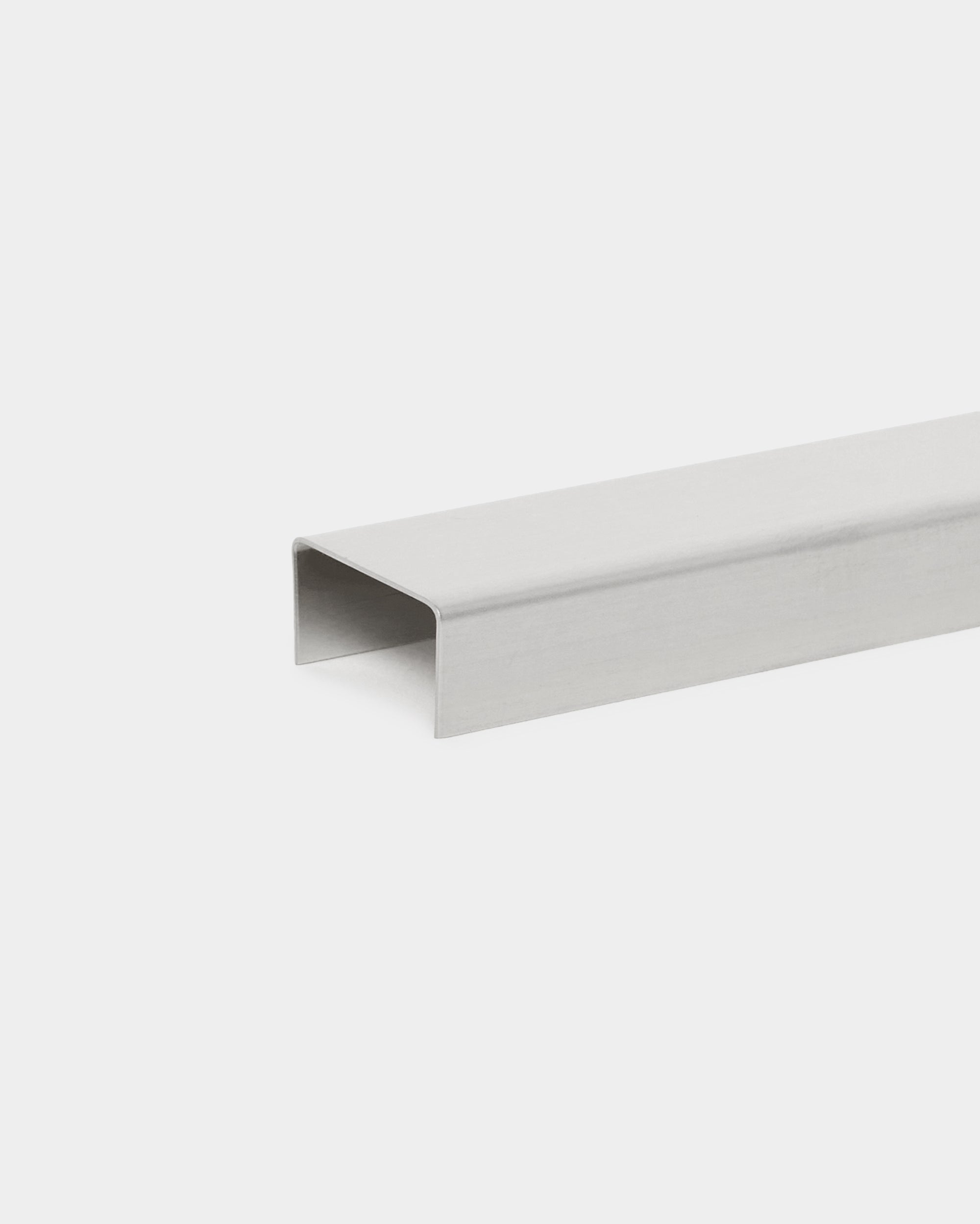 Liva Cover von WoodUpp: 60 cm U-förmiges Metallkanal-Zubehör in poliertem steel, entwickelt zur Verwendung mit Akupanel Akustikpaneelen, dargestellt vor weißem Hintergrund.