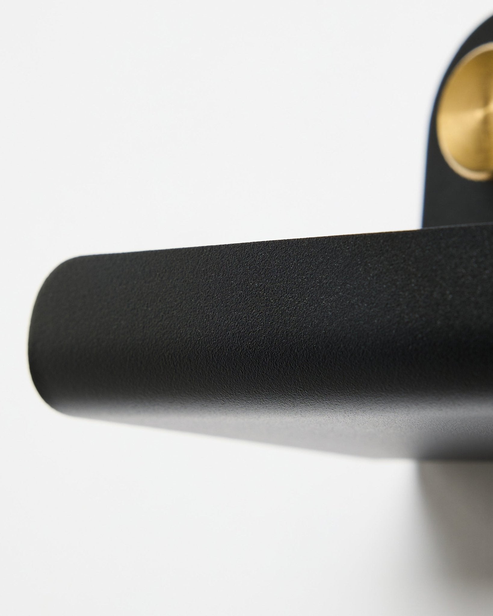 Nahaufnahme eines black Türgriffs und des WoodUpp Norr | Narrow Shelf in black, 51,9 cm, vor weißem Hintergrund.