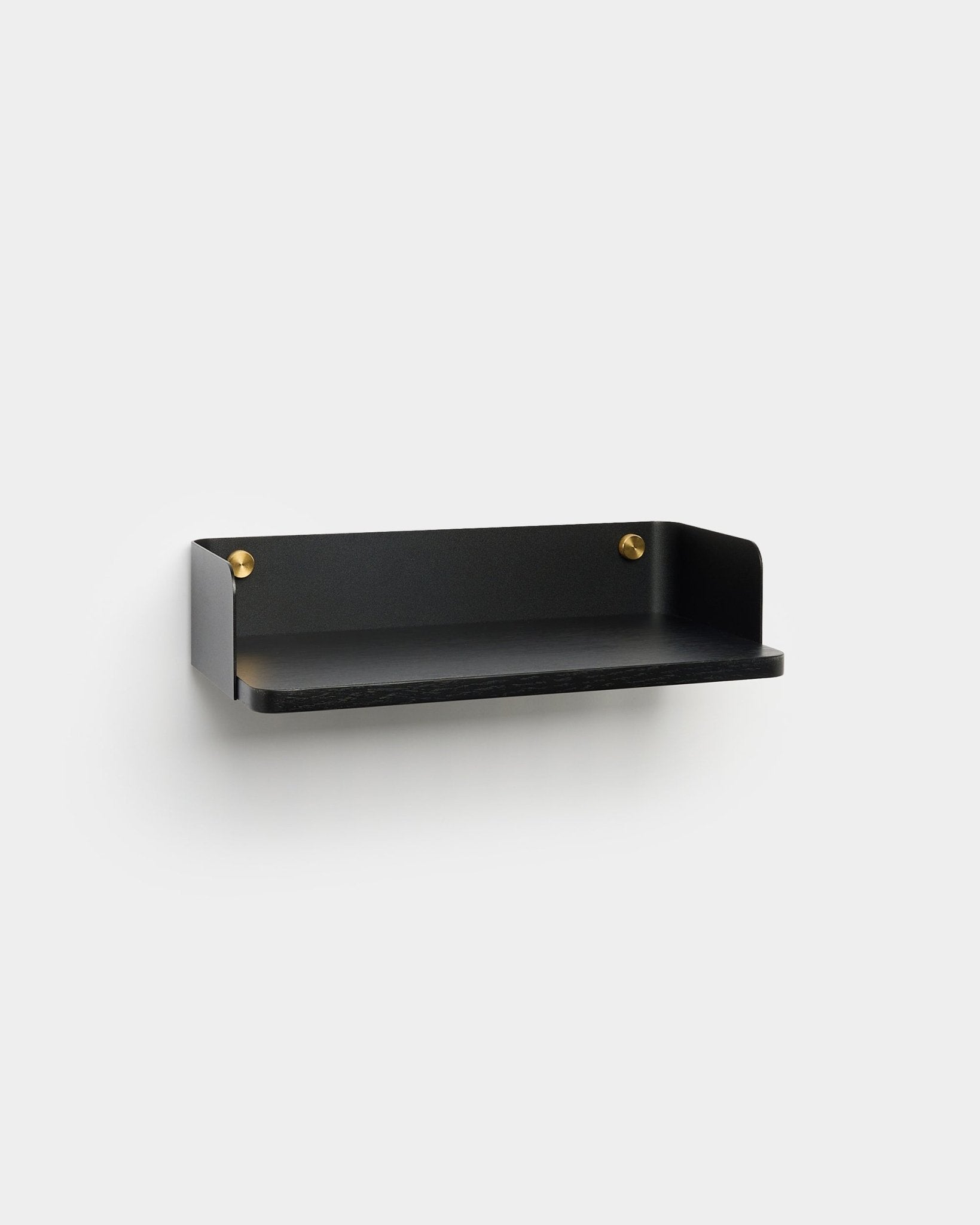 Linn Bücherregal von WoodUpp in einem minimalistischen Finish in black mit Montageschrauben in brass ist an einer hellgrauen Wand montiert und ergänzt das nordische Interior-Design.