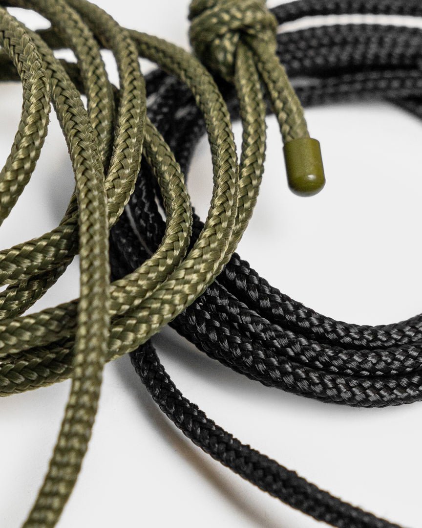 Vindar | Gallery String von WoodUpp: geflochtene grüne und black Kordel mit Kunststoffenden, gezeigt neben einer Fotoleine vor weißem Hintergrund.
