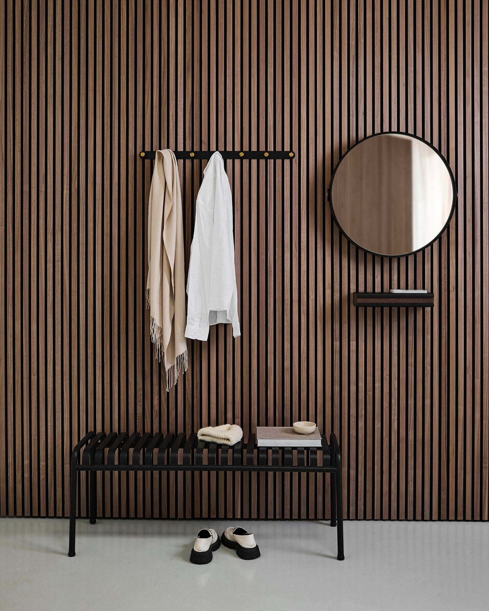 Minimalistischer Eingangsbereich mit einem WoodUpp Linn | Mirror in Black Oak, einer nordischen Akustik-Lamellenwand, einer Bank, einem Regal, aufgehängtem Mantel und Schal sowie Schuhen auf dem Boden.