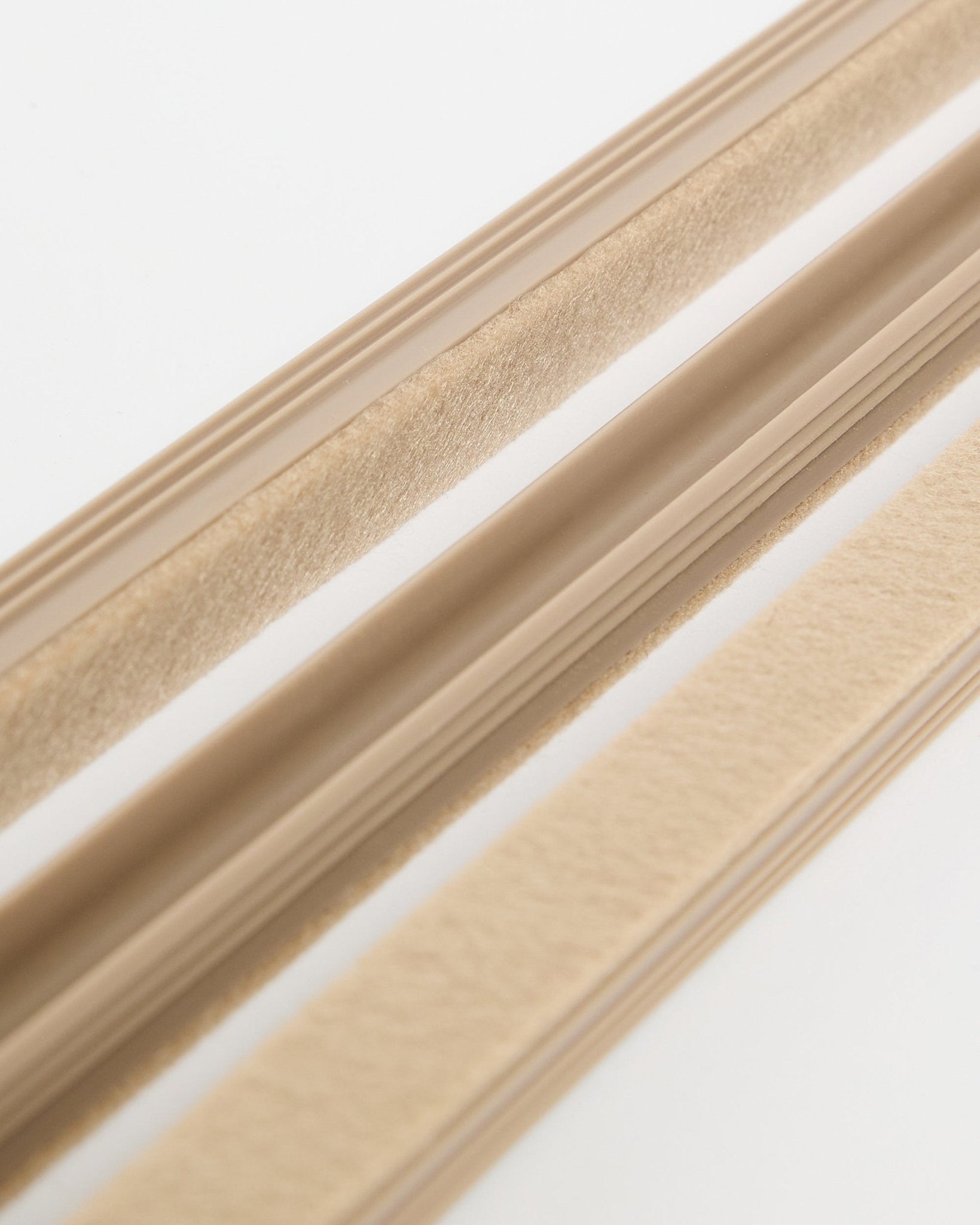Beige WoodUpp Dupps Pop-on Kabelabdeckungen (3er-Pack) mit Filzstruktur und selbstklebender Rückseite, auf einer weißen Oberfläche zur Kabelorganisation gezeigt.