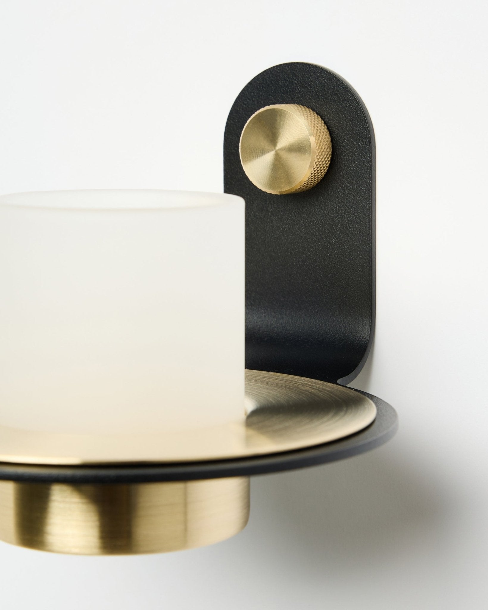 Der Norr Kerzenhalter von WoodUpp in black und brass, gezeigt montiert mit LED-Kerzen auf einem weißen Akustikpaneel.