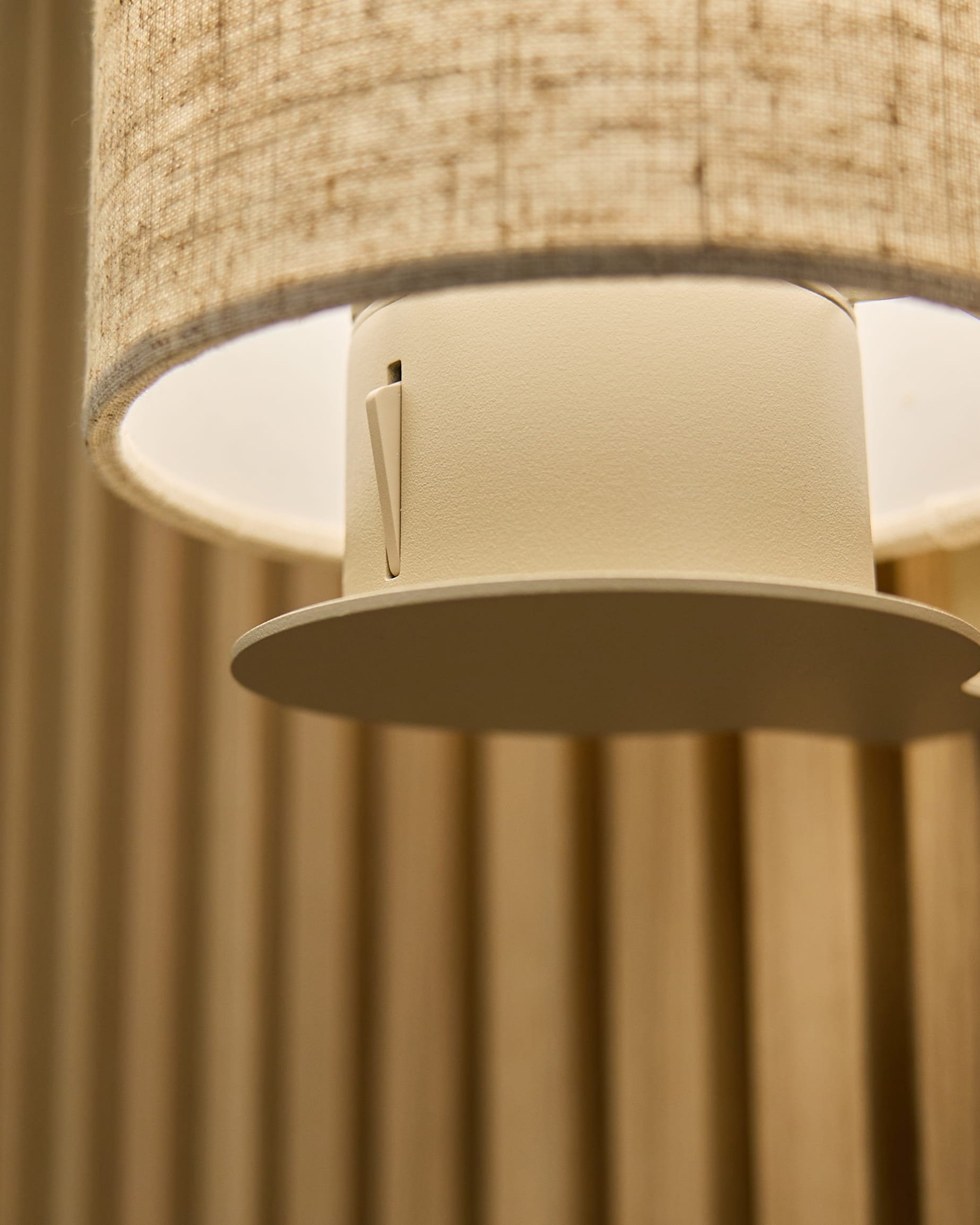 Nahaufnahme der Feya Wandleuchte in Beige/Beige von WoodUpp, mit einem Schirm aus Leinen-Baumwolle und zylindrischer Halterung, montiert auf vertical beige Akustikpaneelen.