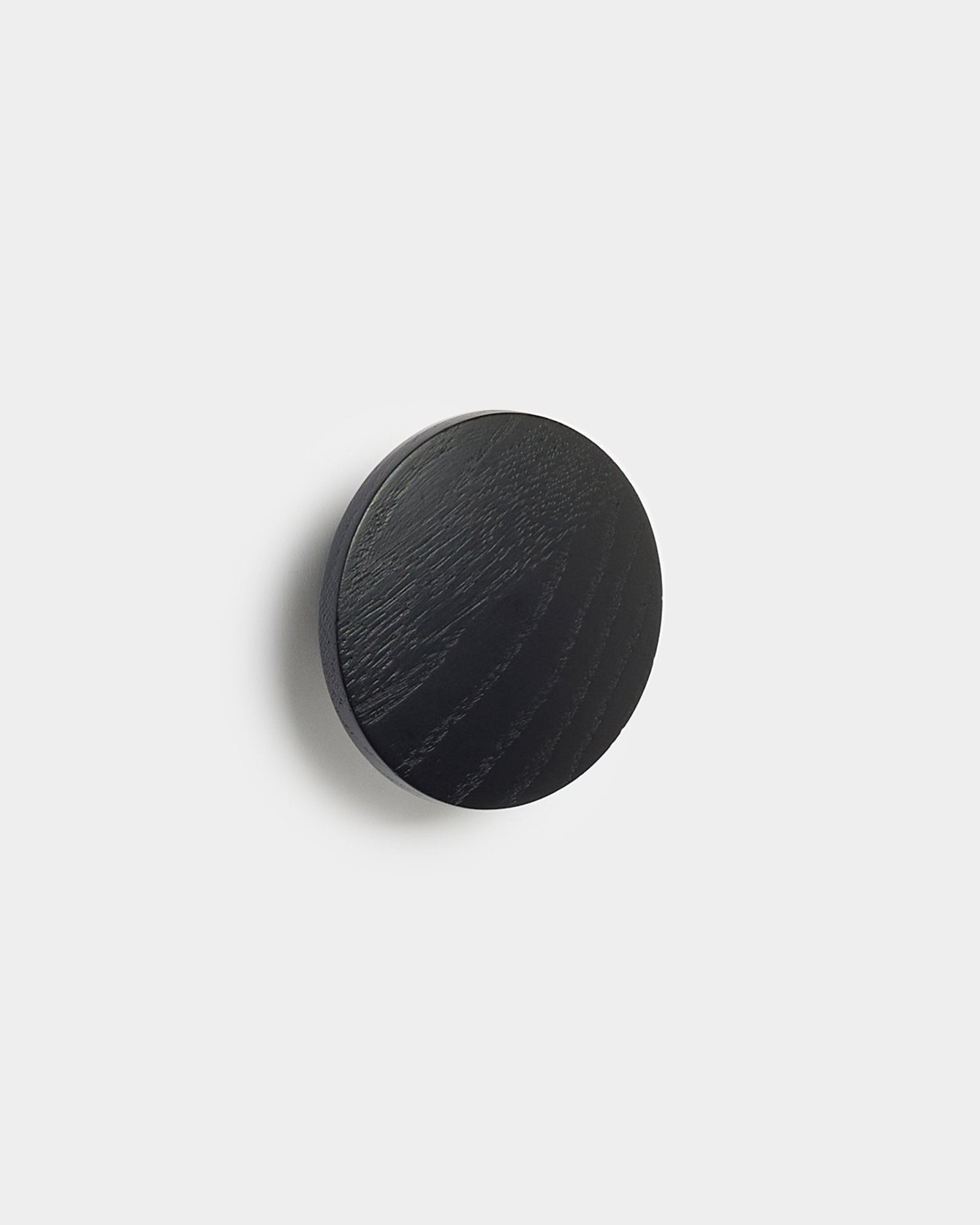 Das Linn | Single Hanger in black oak von WoodUpp, ein rundes Accessoire für Akupanel Akustikpaneele, vor einem schlichten weißen Hintergrund.