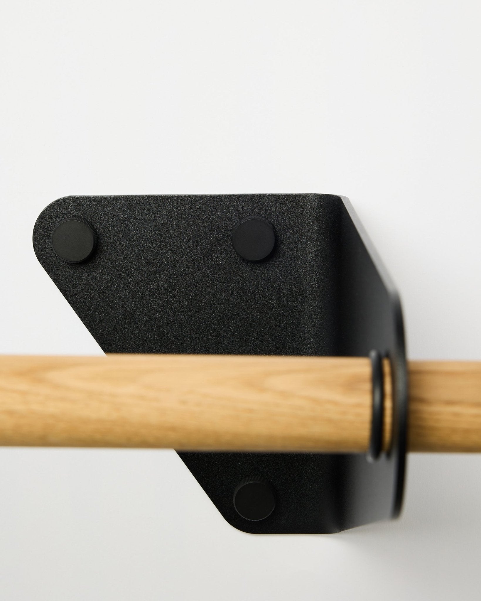 Nahaufnahme der WoodUpp Linn Kleiderstange in black, 115,9 cm, montiert an einer weißen Wand mit dreieckiger Metallhalterung, gezeigt als Teil nordischer Akustik-Accessoires.