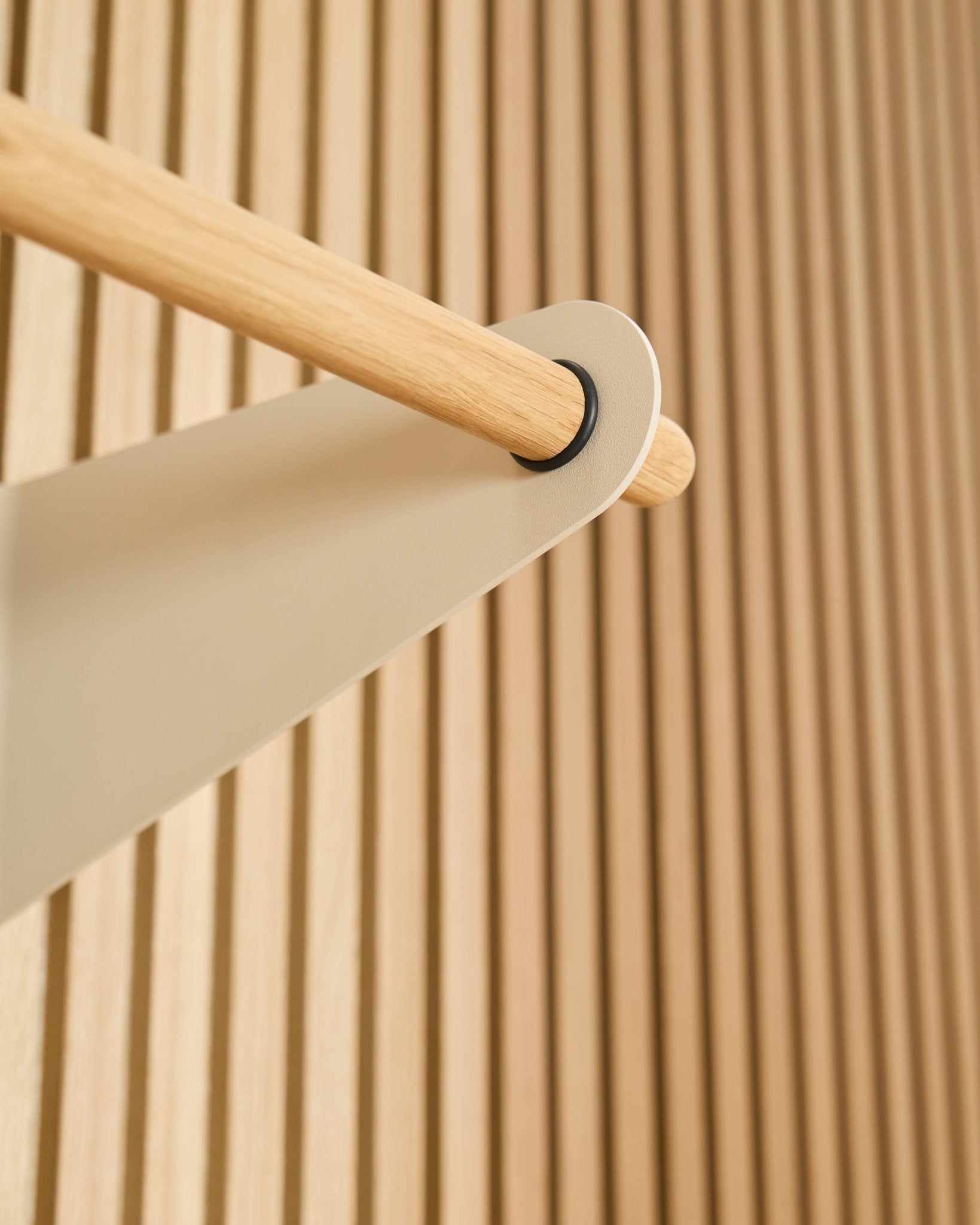 Nahaufnahme der WoodUpp Linn Garderobenstange in beige (75,9 cm), montiert an einer beige Metallhalterung vor einem strukturierten Akustikpaneel mit Lamellen in Akupanel.