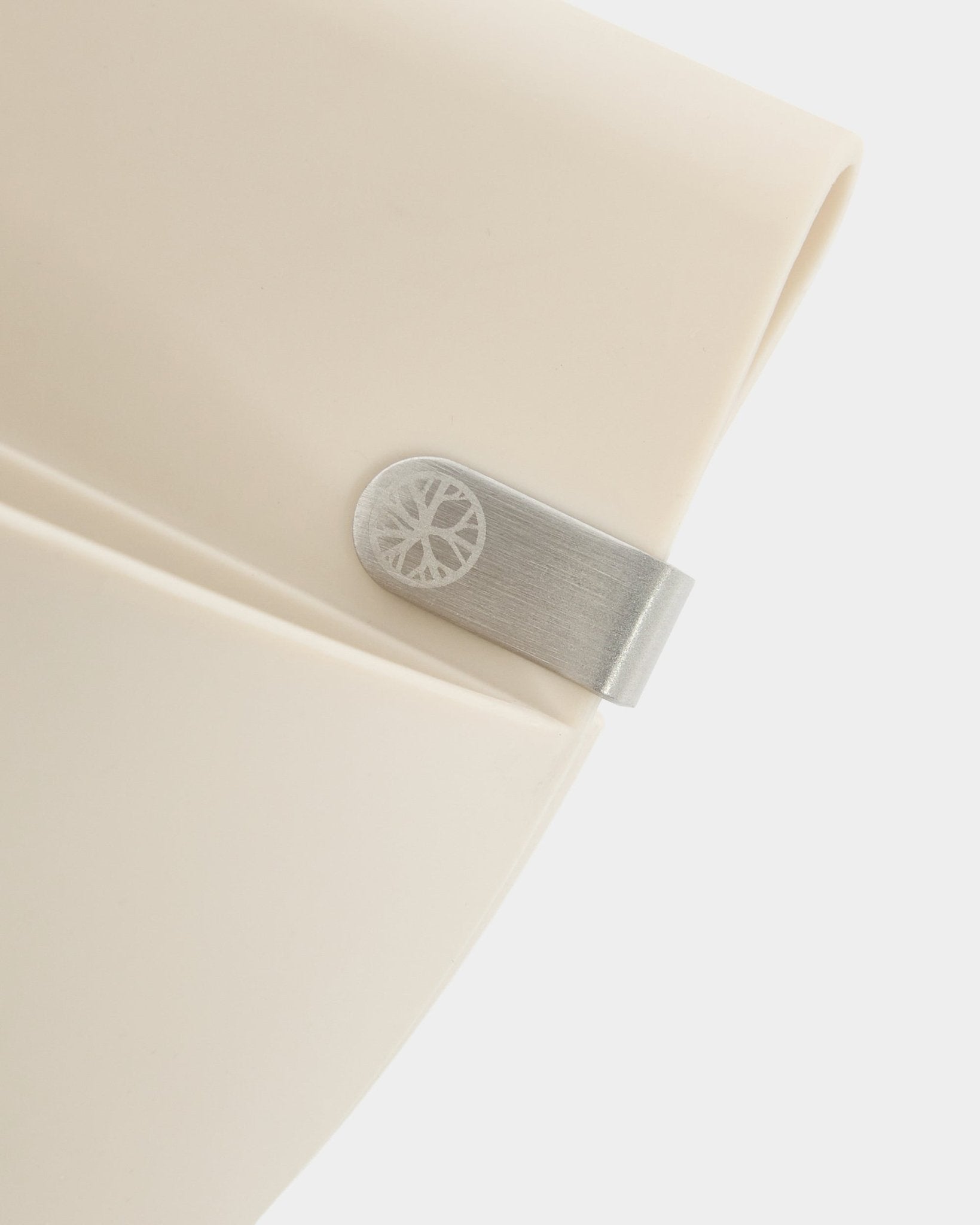 Nahaufnahme eines WoodUpp Gro | Soft Pocket / BM2 (4 l) Paneels in hellem beige mit Metallclip und eingraviertem Kreisdetaill vor schlicht weißem Hintergrund.
