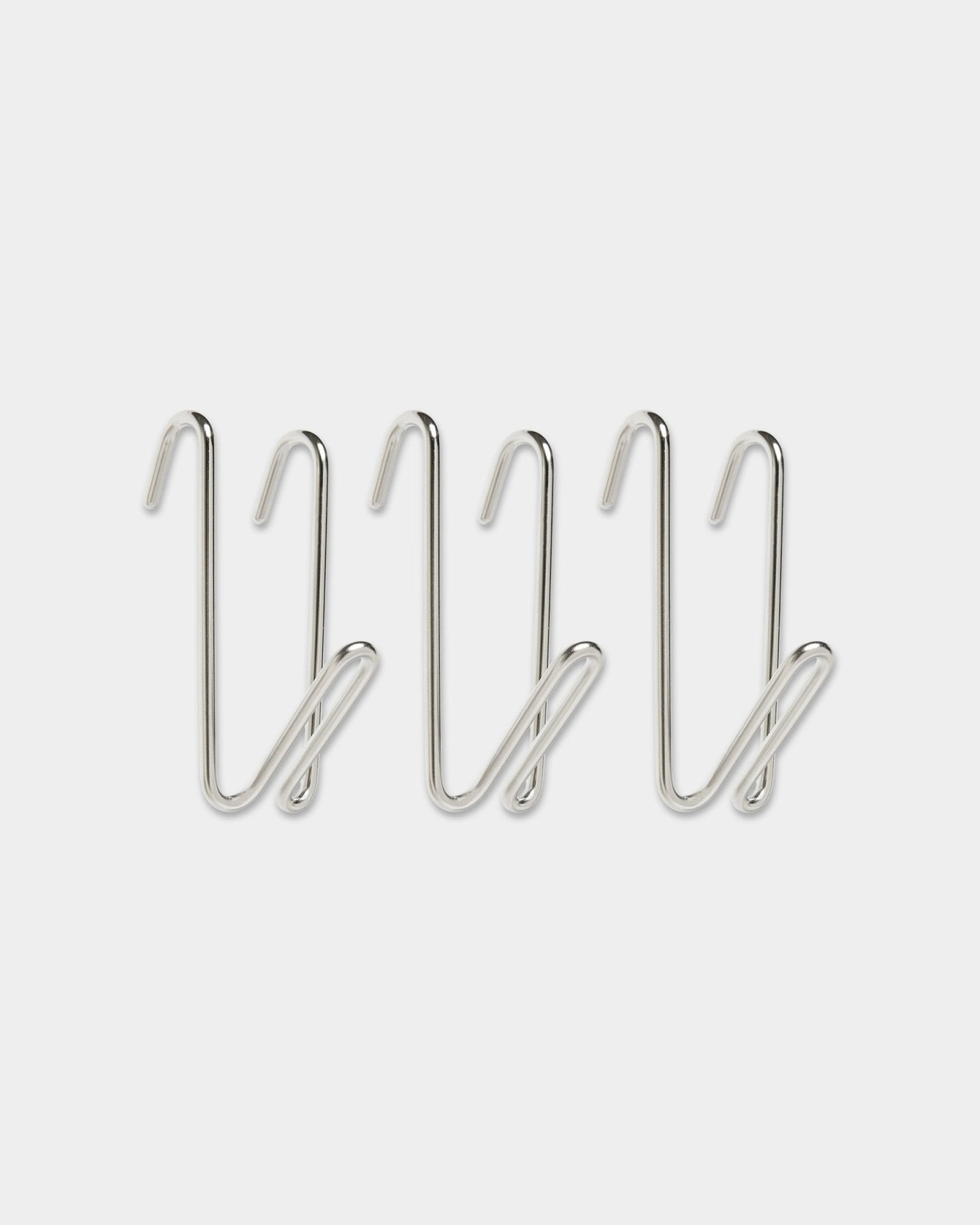 Drei Alva Wire Hooks / BM1 aus Edelstahl steel in der kurzen Ausführung aus WoodUpps CREATE-Kollektion, mit geschwungenem Design, in einer Reihe auf schlicht weißem Hintergrund angeordnet.
