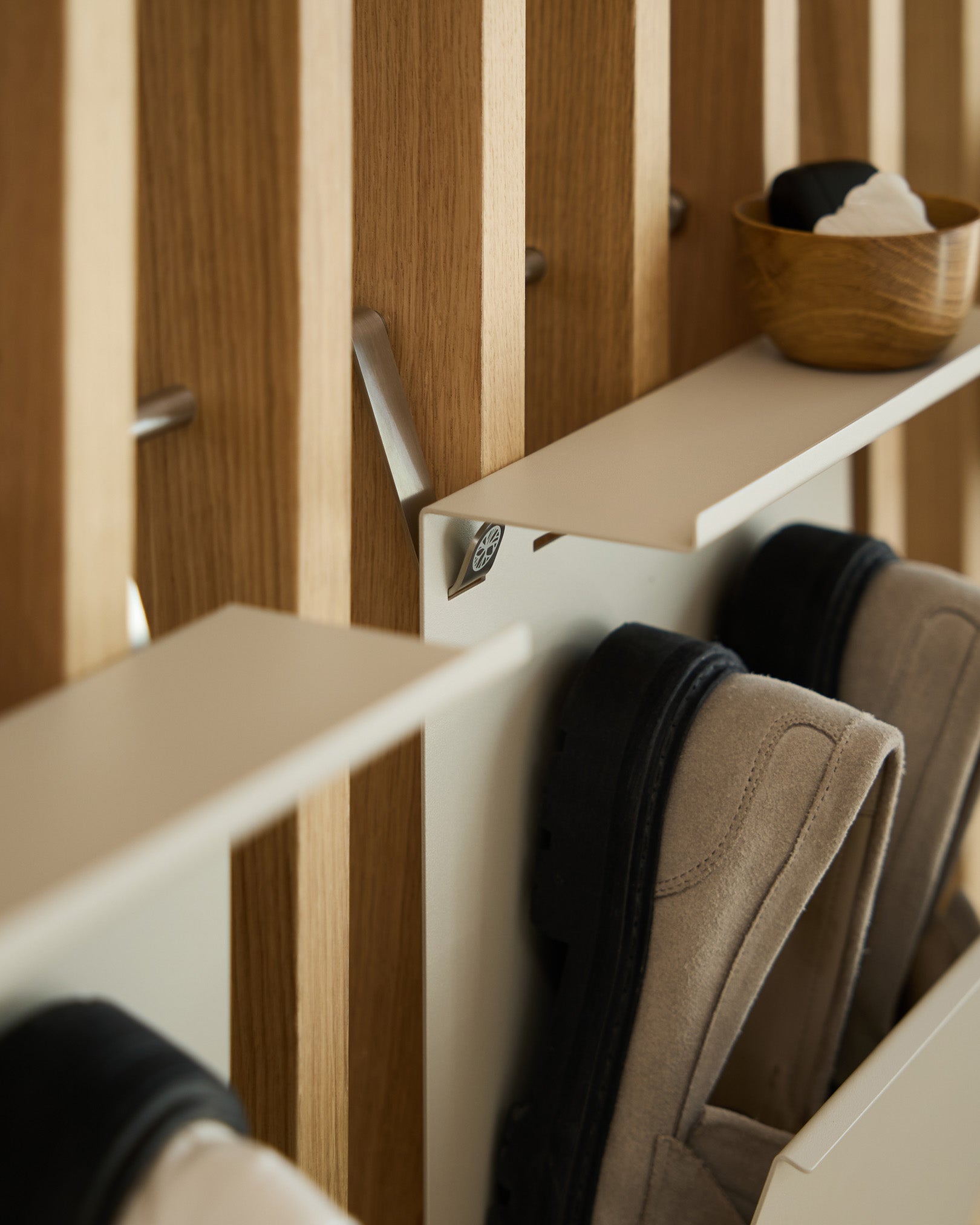 Minimalistischer, pulverbeschichteter Schuhständer von WoodUpp in beige und steel, montiert auf einer nordischen Lamellenwand Akustikpaneel; darüber steht eine small Schale für Schlüssel.