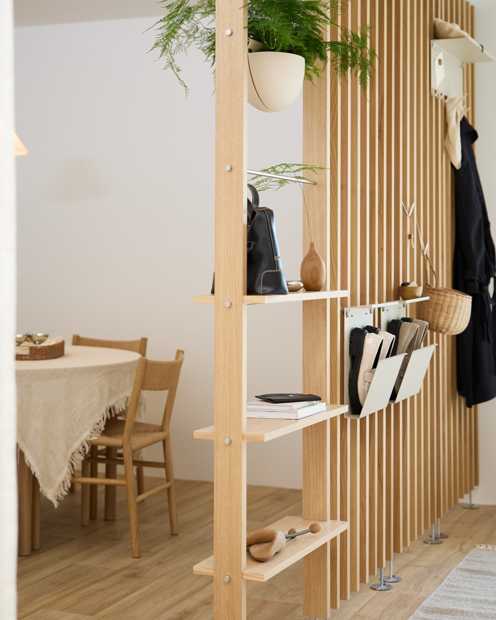 Offene Holzregale teilen den Essbereich und zeigen die Nell Schuhaufbewahrung in beige von WoodUpp für ordentlich organisierten Stauraum für Schuhe in einem modernen nordischen Zuhause.