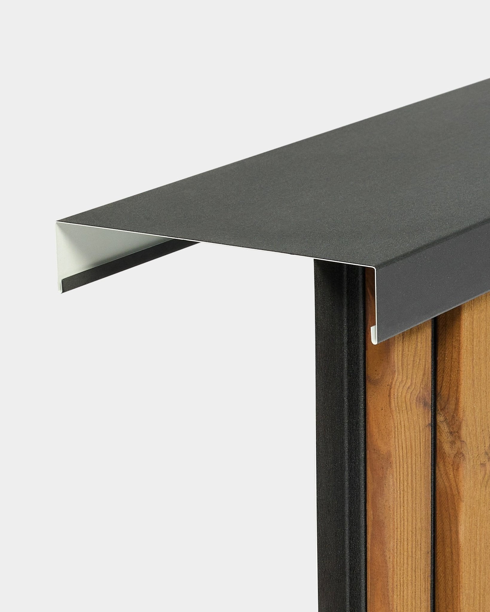 Nahaufnahme des montierten Aluwood Level Wandabschlusses von WoodUpp (240 cm x 25 cm) auf vertical Fassadenpaneelen, mit Fokus auf das Kantendetail vor schlichtem Hintergrund.