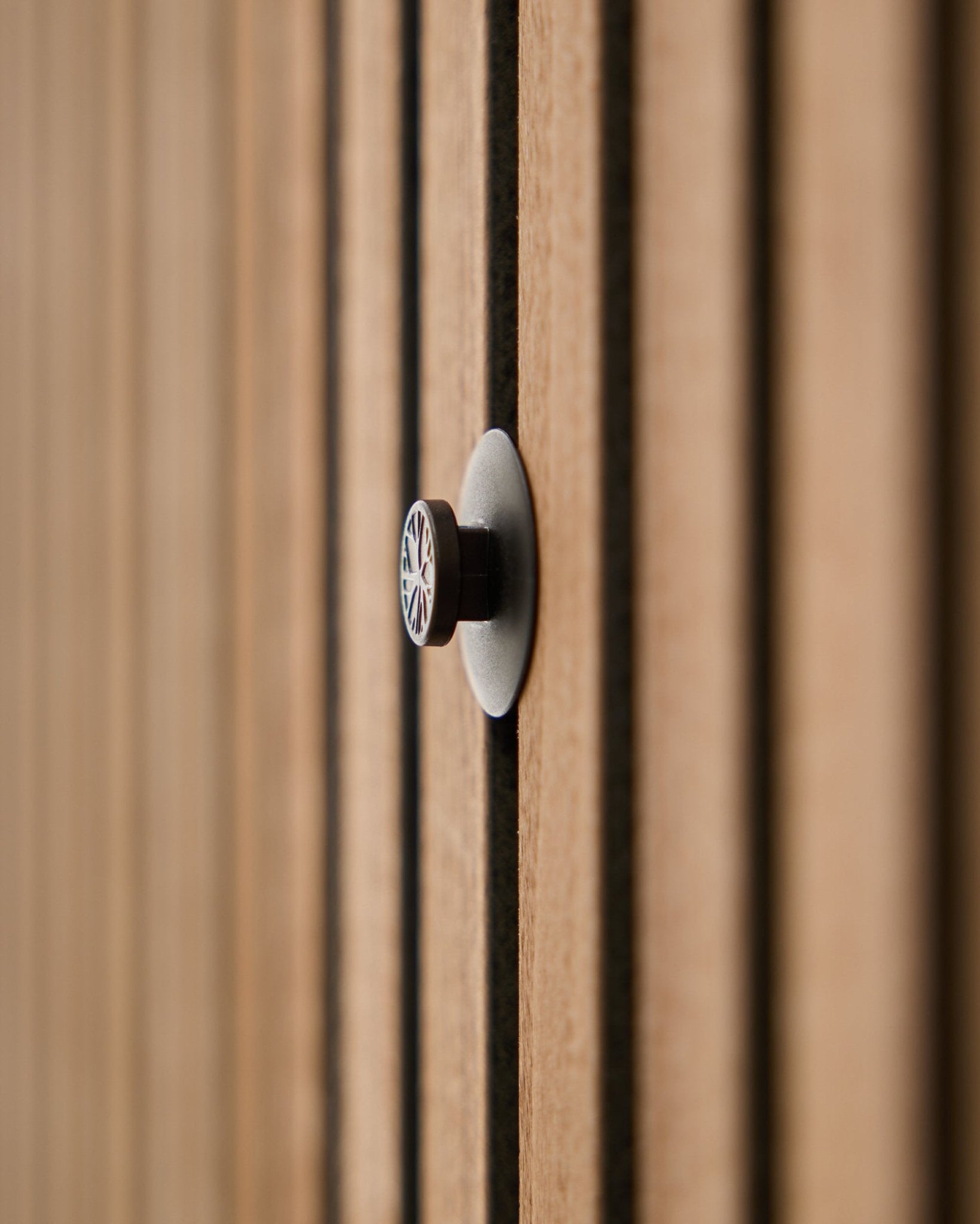 Nahaufnahme eines montierten Dupps | Light Knopf-Sets (3 Knöpfe plus Werkzeug) von WoodUpp auf einer Akustik-Lamellenwand, mit sanft unscharfen Holzlamellen im Hintergrund.