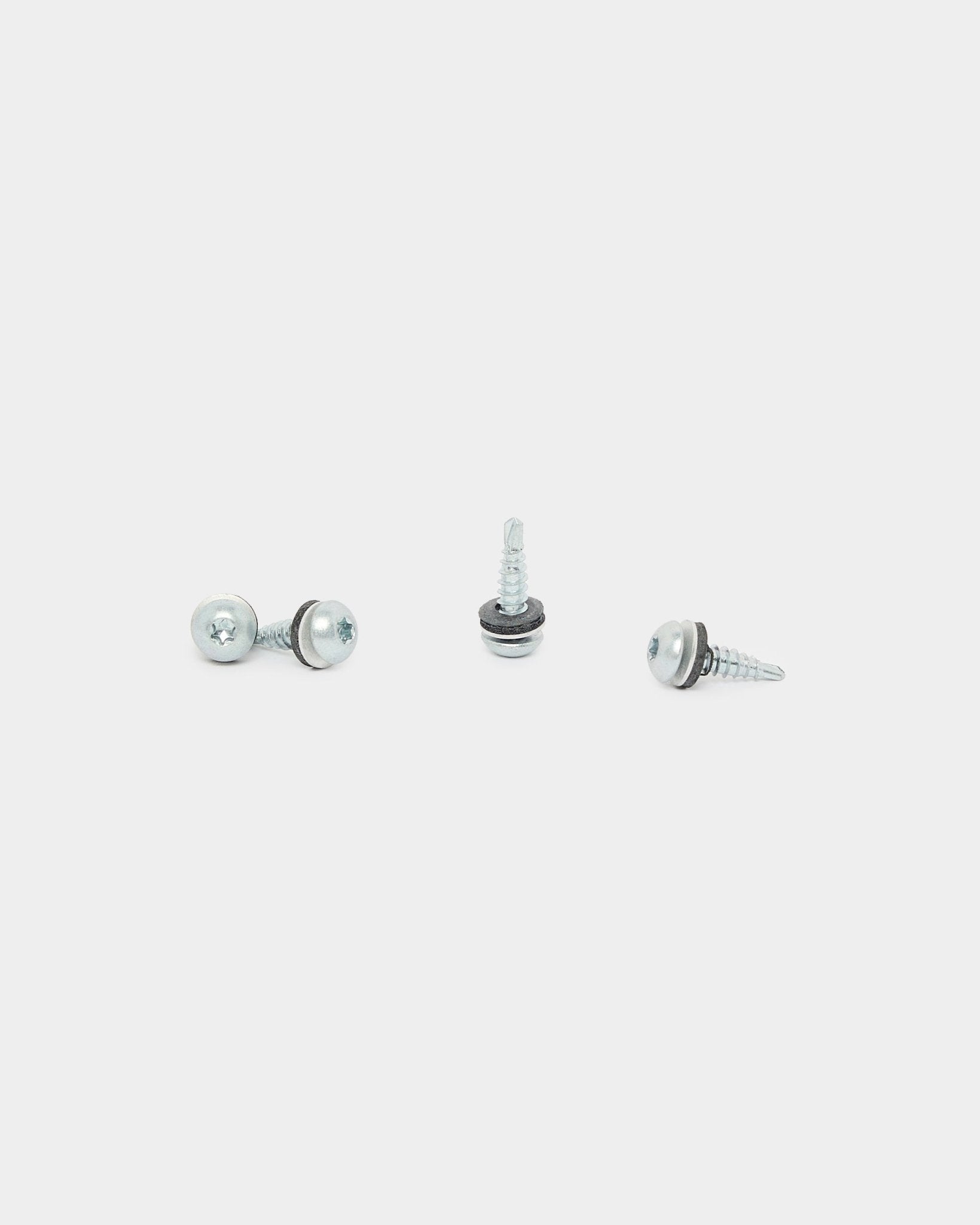 Drei black WoodUpp Backside Screws (4.8x19, Ø10 Unterlegscheibe, TX20), verwendet für die Installation von Akustikpaneel, sind auf weißem Hintergrund in unterschiedlichen Richtungen angeordnet.