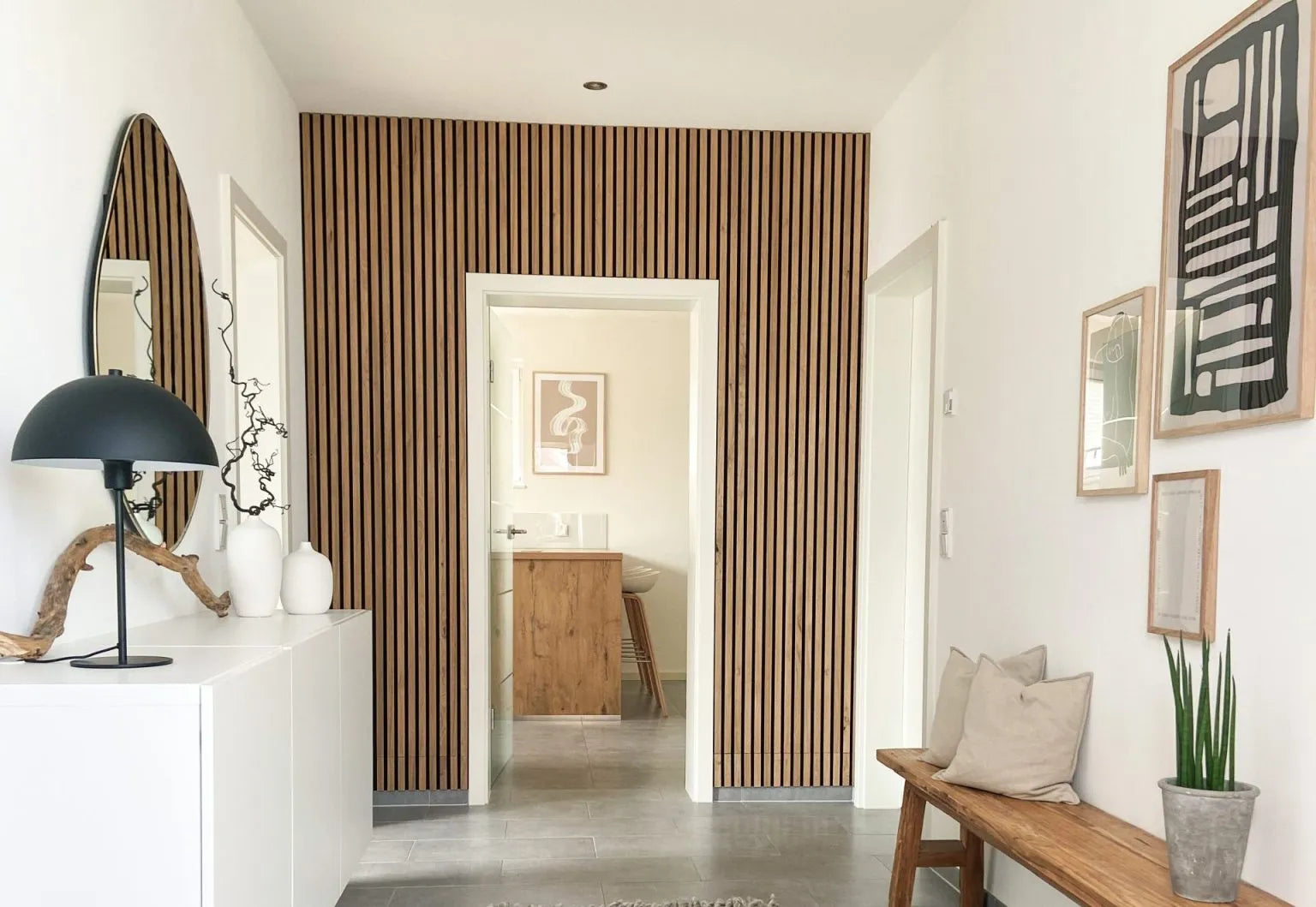Ein moderner Flur mit einer Akustikwand aus nordischen Akupanel-Holzlatten, weißen Wänden, einer gepolsterten Bank und minimalistischem Dekor.