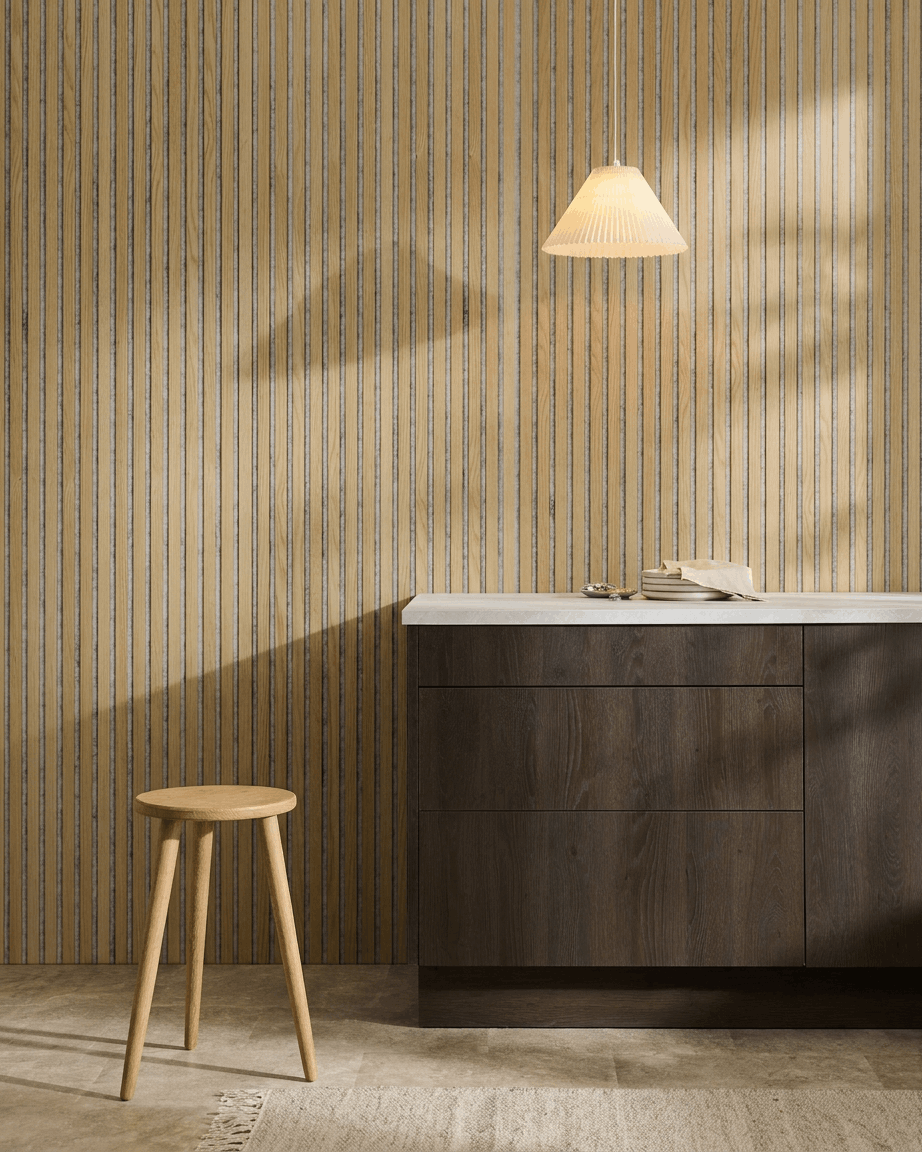 Minimalistisches nordisches Interieur mit einem WoodUpp Akupanel Akustikpaneel in Classic Oak mit Filz in Grey, kombiniert mit einem Holzstuhl, einem dunklen Schrank und einer weißen Arbeitsplatte.
