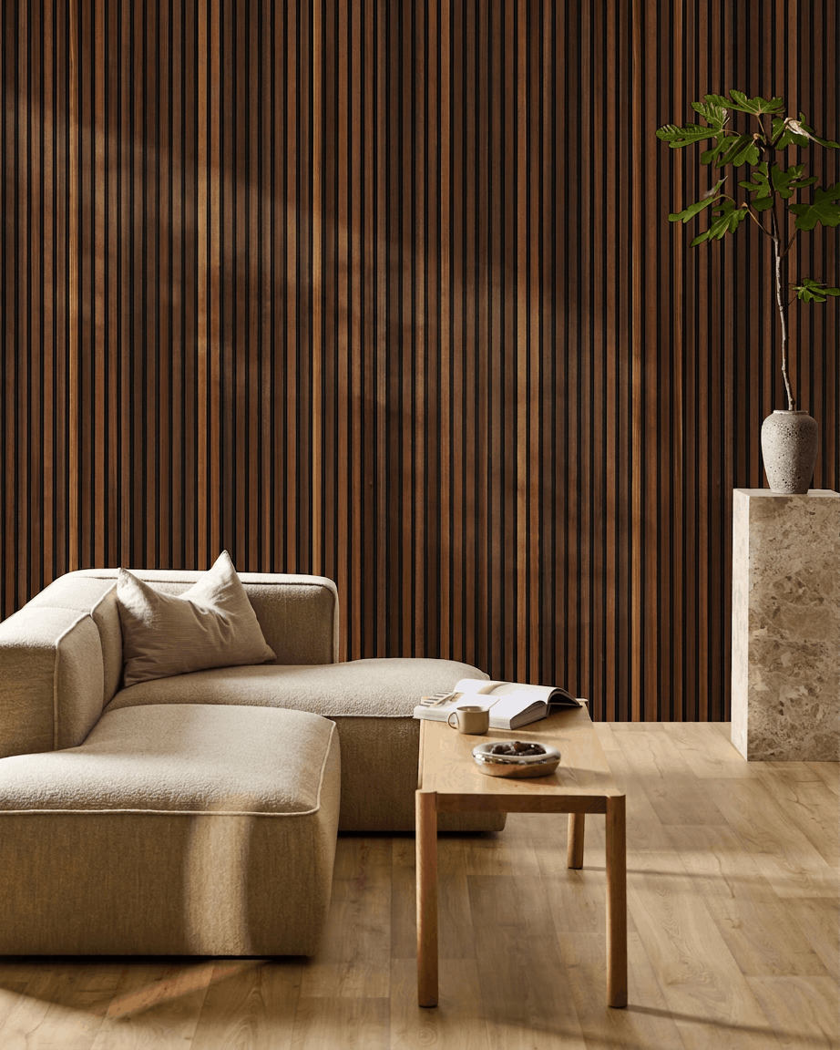 Minimalistisches Wohnzimmer mit einem beige Sofa, einem Couchtisch mit offenem Buch, einer hohen Pflanze und einem WoodUpp Akupanel Akustik-Holzpaneel in smoked larch an der Wand.
