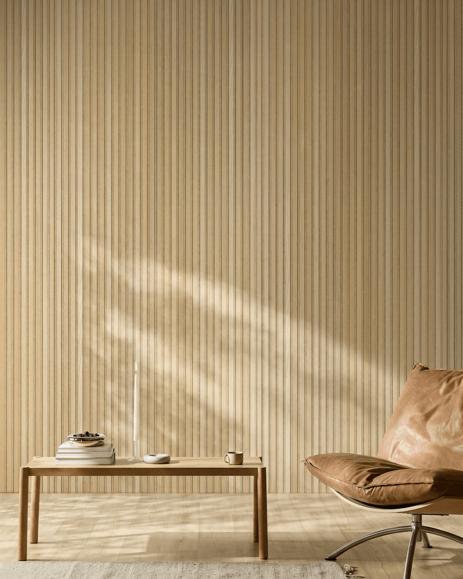 Minimalist Scandinavian room featuring a WoodUpp Akupanel acoustic wood panel in Natural Wood Classic Oak, tan leather chair, and simple wooden table with cozy accents.