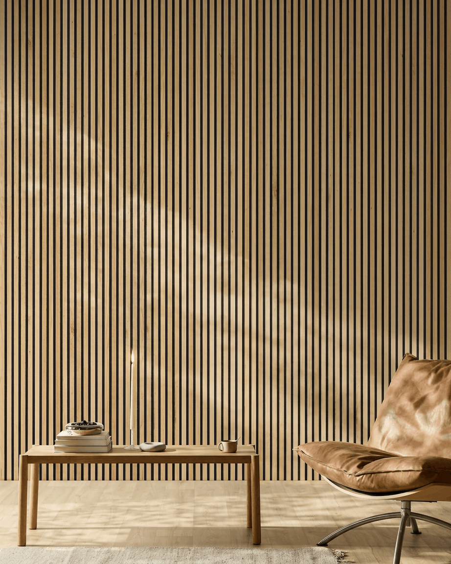 Sonnenlicht erhellt einen modernen Raum mit einem WoodUpp Akupanel Akustikpaneel in Rustic Natural Oak an der Wand, zusammen mit einem hellbraunen Ledersessel und einer minimalistischen Bank.