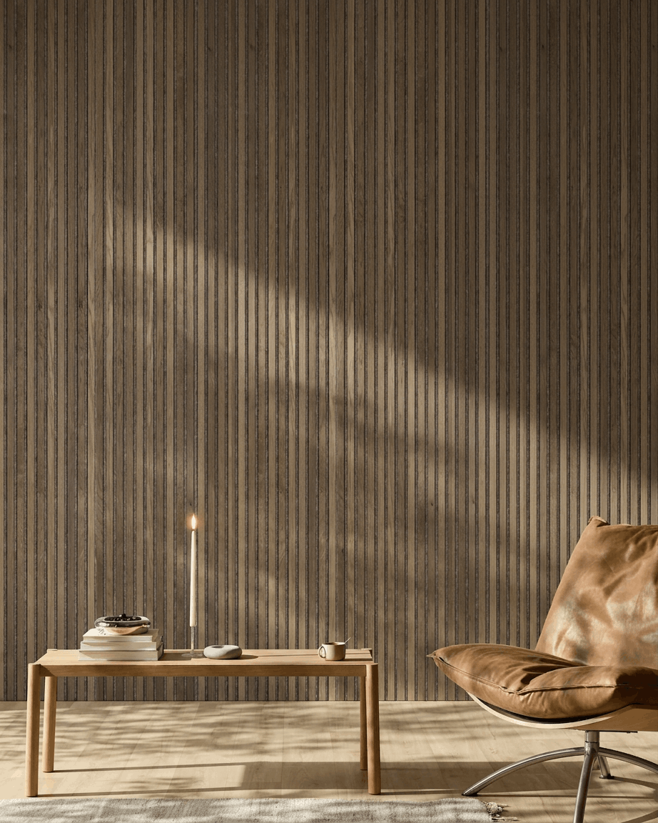 Ein moderner Raum mit einem brown Ledersessel, einem Holztisch und einem an der Wand montierten WoodUpp Akupanel in Rustic Grey Oak, beleuchtet von sanftem Sonnenlicht.