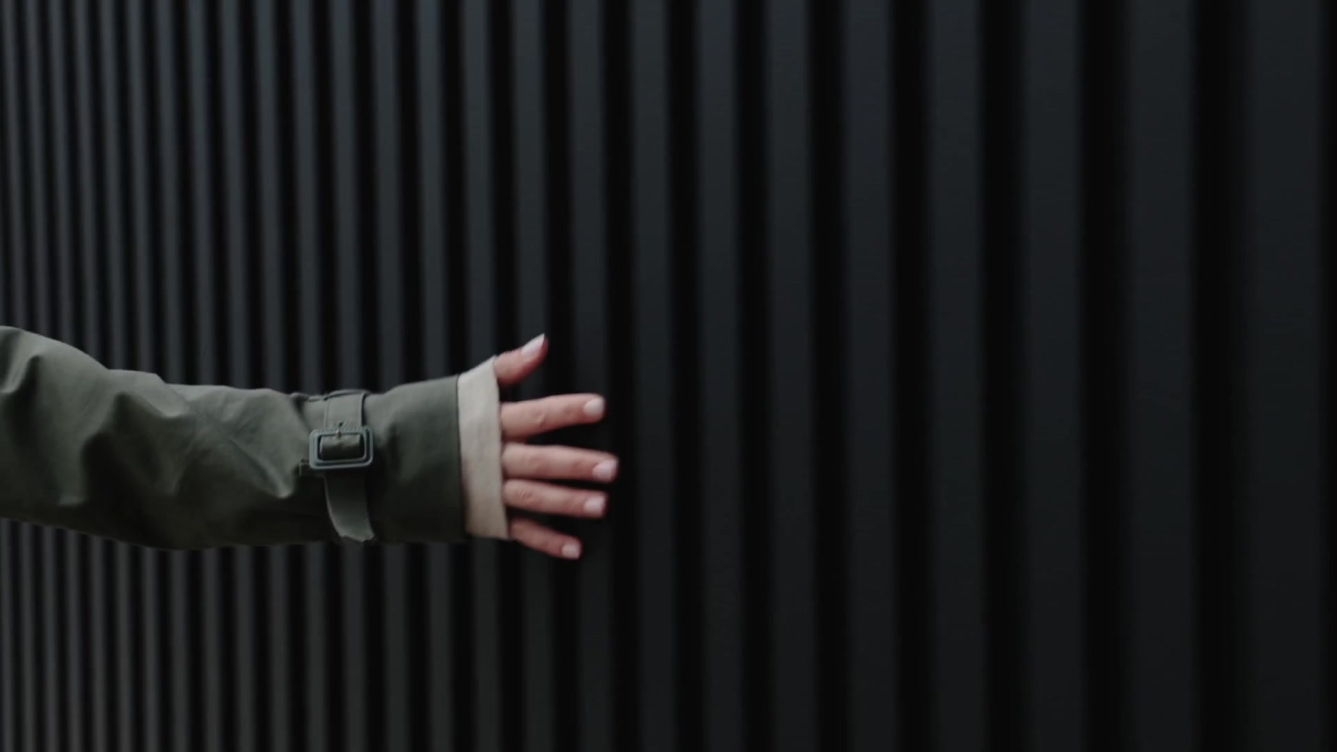 Hand resting on a black vertically slatted garage wall