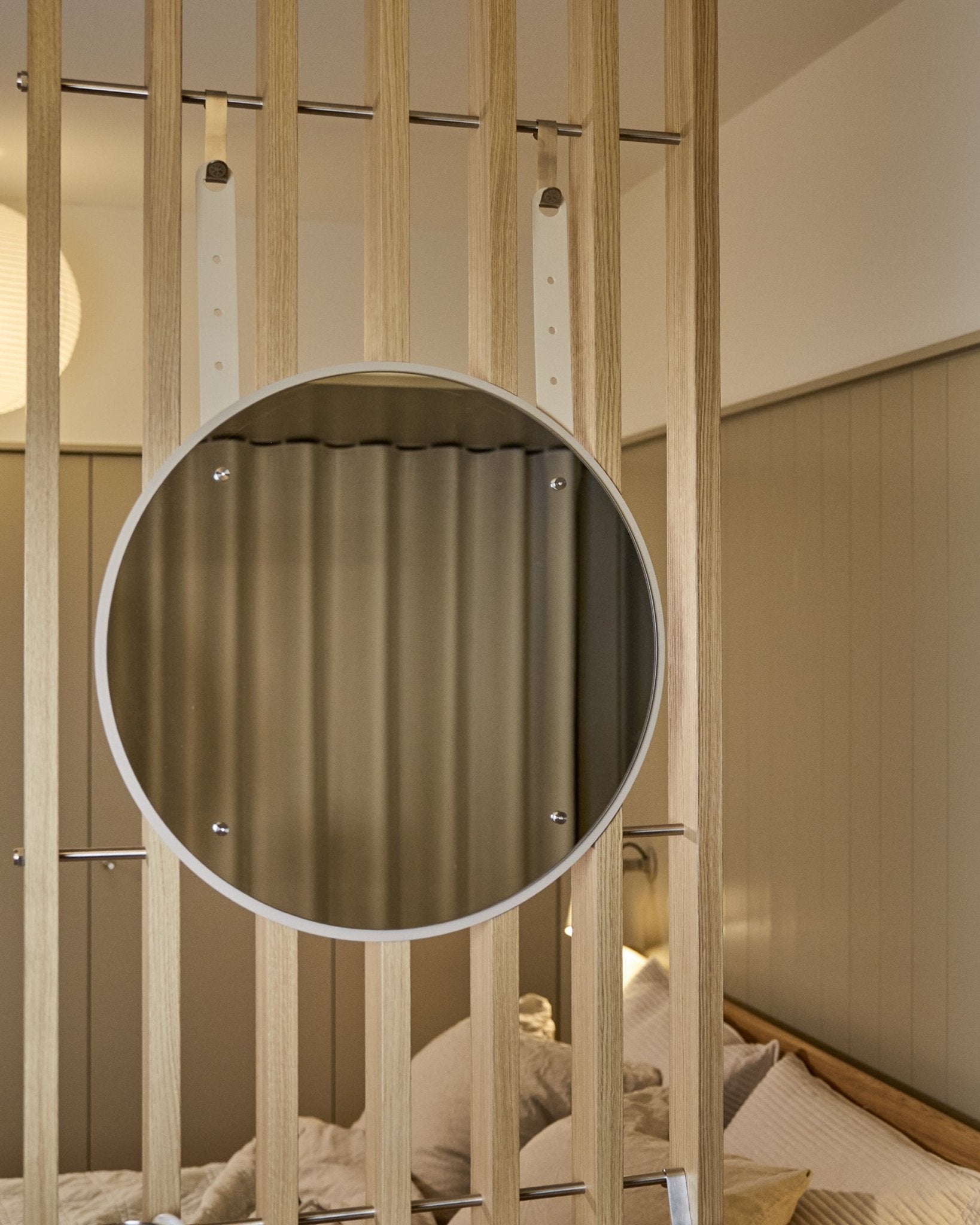 Runder, höhenverstellbarer Vala BM1 Spiegel von WoodUpp, 54 cm Durchmesser, montiert auf vertical Akustik-Holzlamellenpaneel bei weichem, neutralem Licht.