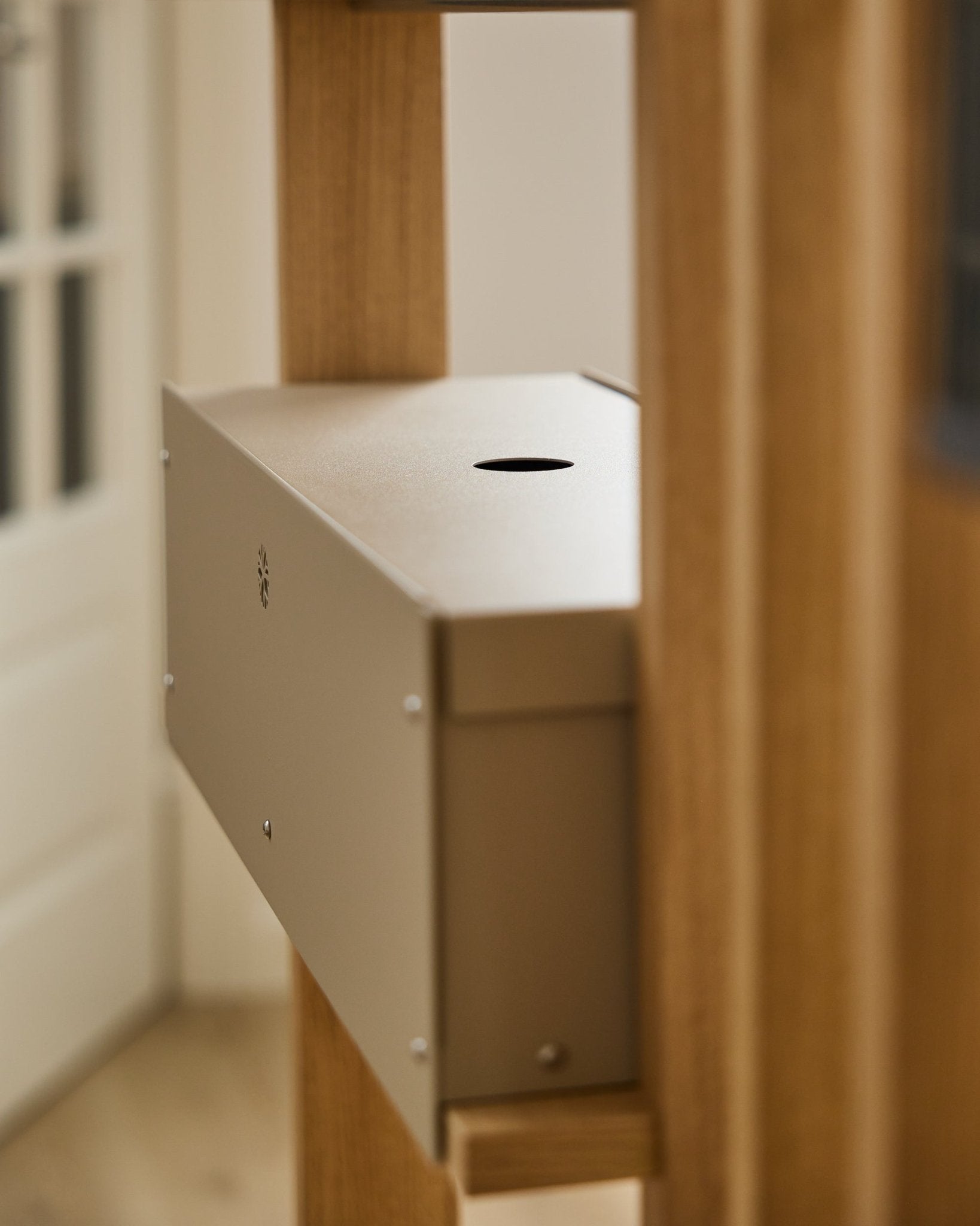 Das Nell | Metal Box / BM2, Beige von WoodUpp ist ein pulverbeschichtetes Zubehör aus steel aus der CREATE Kollektion, platziert zwischen Akustik-Holzpaneelen neben einer weißen Tür.